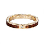 In this photo there is a yellow gold koa wood ring with hand engravings of scrolls and one diamond.