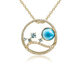 In this photo there is a yellow gold circle pendant with blue larimar, aquamarine, and diamonds.
