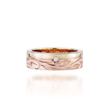 The picture shows a 14K yellow and rose gold two-tone pinched channel 6mm ring with a diamond and hand-engravings.