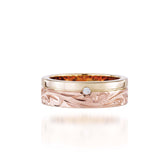 The picture shows a 14K yellow and rose gold two-tone pinched channel 6mm ring with a diamond and hand-engravings.