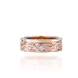 The picture shows a 14K yellow and rose gold two-tone wave channel 6mm ring with a diamond and hand-engravings.