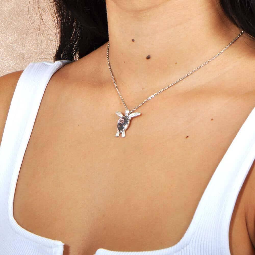 Abalone shell sterling silver sea turtle pendant worn by a model.