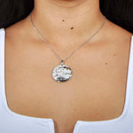 A model wearing a Sterling silver medallion pendant with a turtle swimming away from the abalone tides.