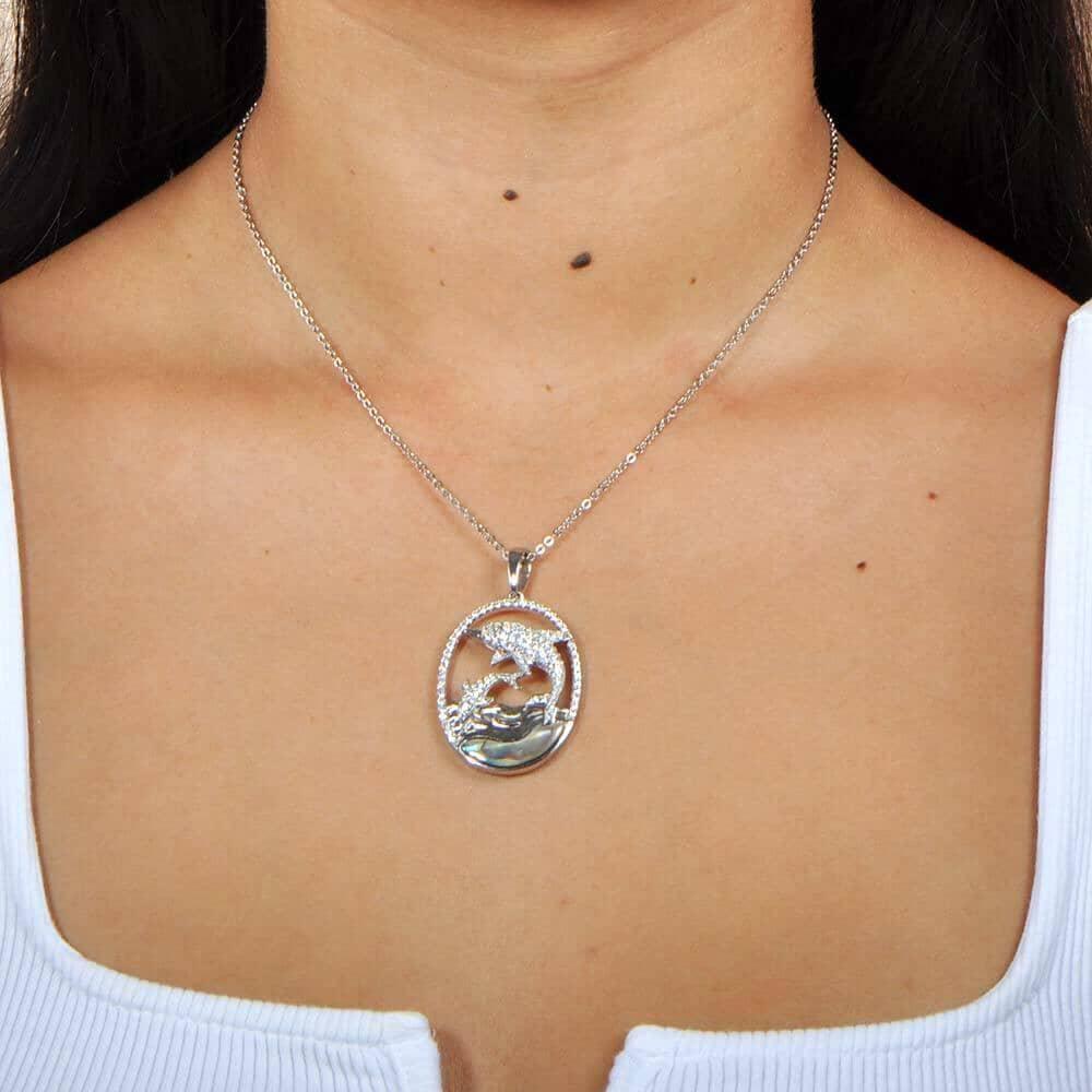 Sterling Silver, white topaz, and abole pendant designed like two dolphins. The pendant is worn by a model.