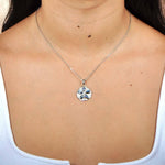 Sterling silver sand dollar pendant featuring Pave and iridescent abalone worn by a model