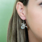 The picture shows a model wearing a 925 sterling silver turtle hatchling hook earring.