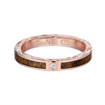 In this photo there is a rose gold koa wood ring with hand engravings of scrolls and one diamond.