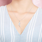 The picture shows a model wearing a 925 sterling silver mermaid pendant and a blue shirt with blue lines.