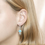 The picture shows a model wearing a 925 sterling silver larimar jellyfish lever back earring with topaz