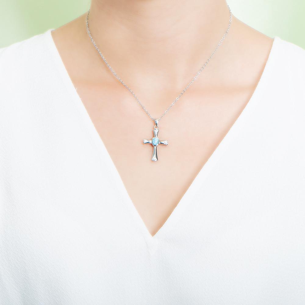 The picture shows a model wearing a 925 sterling silver larimar centered cross pendant.