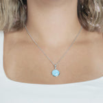 The picture shows a model wearing a 925 sterling silver larimar circle pendant.