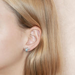 The picture shows a model wearing a 925 sterling silver a larimar sea turtle stud earring.