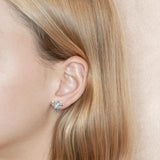 The picture shows a model wearing a 925 sterling silver a larimar sea turtle stud earring.