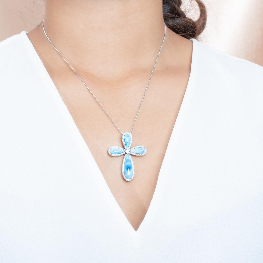 The picture shows a model wearing a 925 sterling silver larimar cross pendant with topaz.