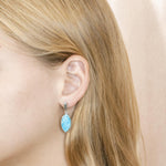 The picture shows a model wearing a 925 sterling silver larimar mandorla earring.