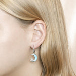 The picture shows a model wearing a 925 sterling silver larimar moon and star lever-back earring.