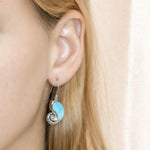The picture shows a model wearing a 925 sterling silver larimar shell hook earring.
