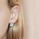The picture shows a model wearing a 925 sterling silver larimar oyster shell stud earring.