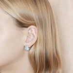 The picture shows a model wearing a 925 sterling silver larimar oyster shell stud earring.