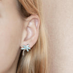 In this photo there is a model wearing 925 sterling silver palm tree stud earrings with larimar gemstones.