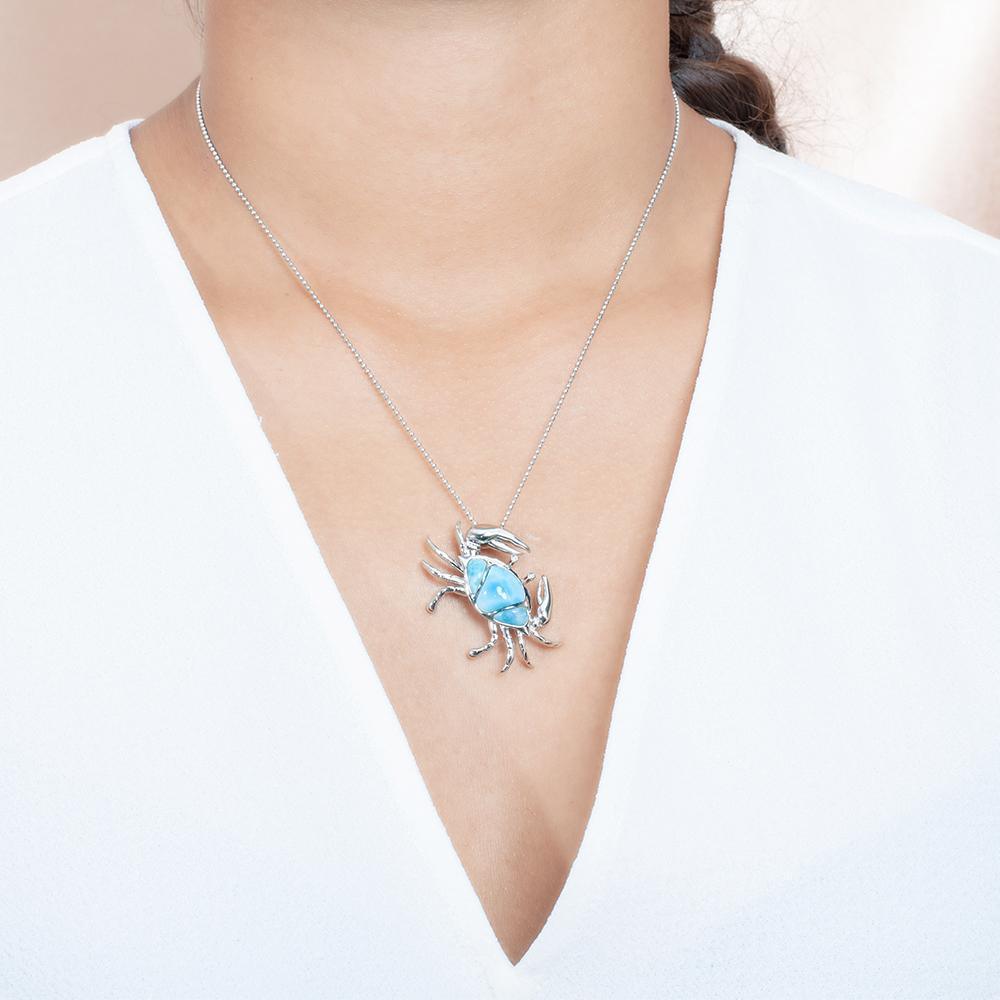 The picture shows a model wearing a 925 sterling silver larimar sand dune blue crab pendant.