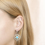 The picture shows a model wearing a 925 sterling silver larimar star lantern lever-back earring with topaz