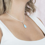 The picture shows a model wearing a 925 sterling silver larimar starry sky teardrop pendant with cubic zirconia.