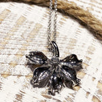 In this photo there is a white gold naupaka flower pendant with one diamond.