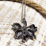 In this photo there is a white gold naupaka flower pendant with one diamond.