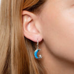 The picture shows a model wearing a 925 sterling silver opalite moon and star earring and topaz.