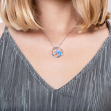In this photo there is a model with blonde hair and a gray shirt, wearing a sterling silver big wave circle pendant with blue opalite gemstones.
