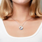 The picture shows a model wearing a 925 sterling silver opalite ocean wave pendant with cubic zirconia.