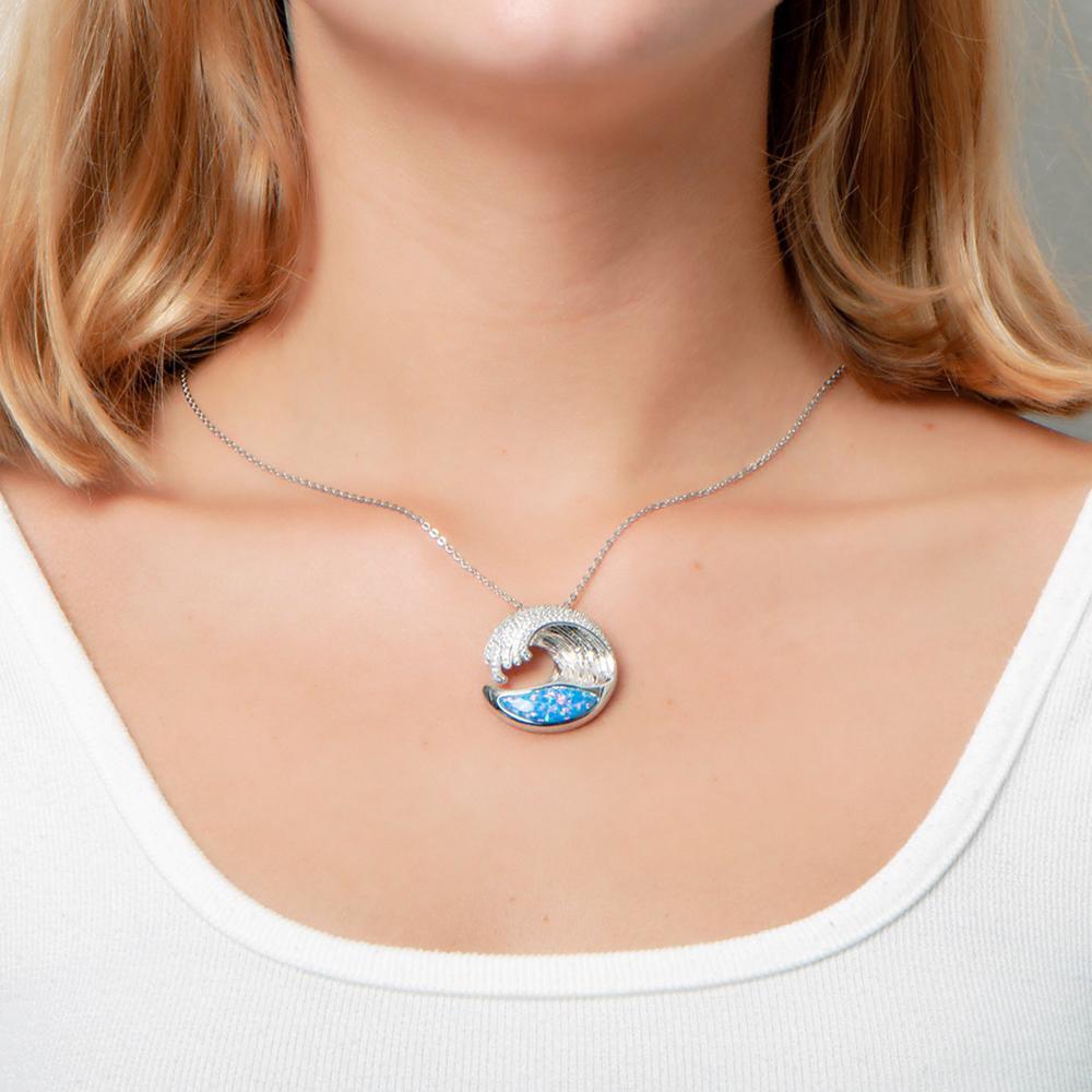 The picture shows a model wearing a 925 sterling silver opalite ocean wave pendant with cubic zirconia.