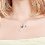 The picture shows a model wearing a large 925 sterling silver dolphin pendant with cubic zirconia.