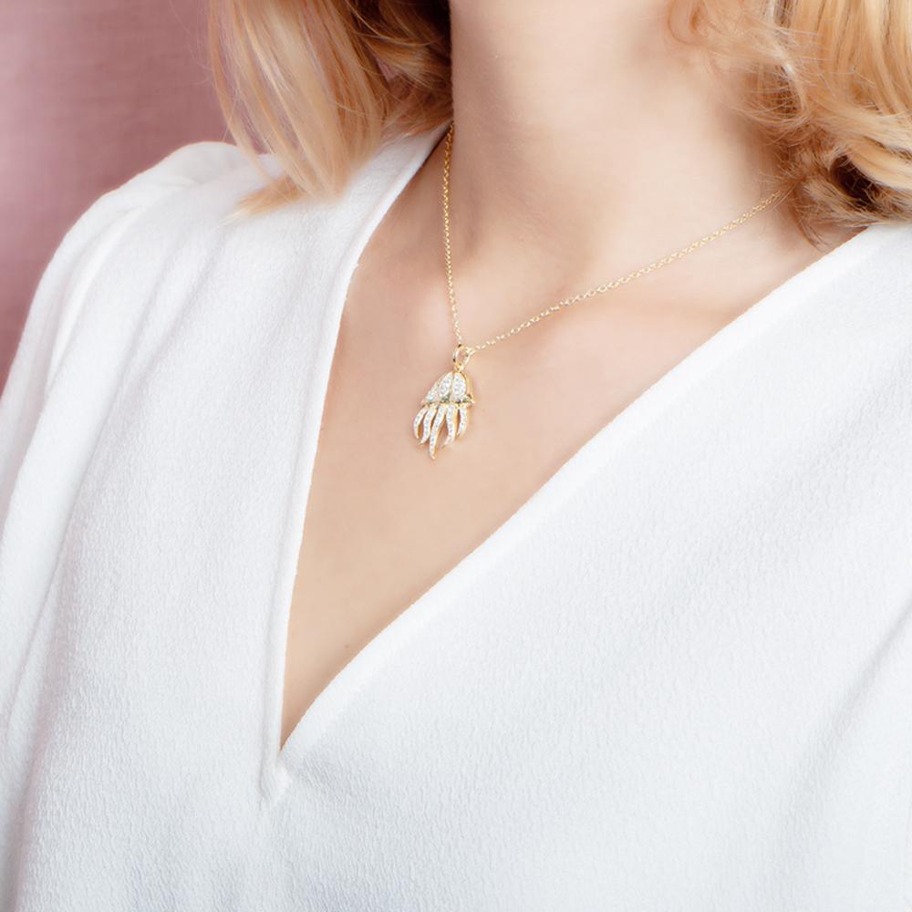 The picture shows a model wearing a 925 sterling silver, yellow gold plated, pavé barrel jellyfish pendant with topaz.