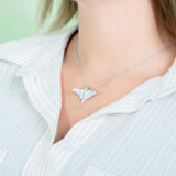 The picture shows a model wearing a 925 sterling silver, white gold plated, pavé eagle ray pendant with cubic zirconia.