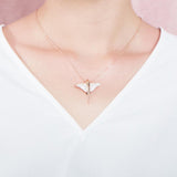 The picture shows a model wearing a 925 sterling silver, rose gold plated, pavé eagle ray pendant with cubic zirconia.