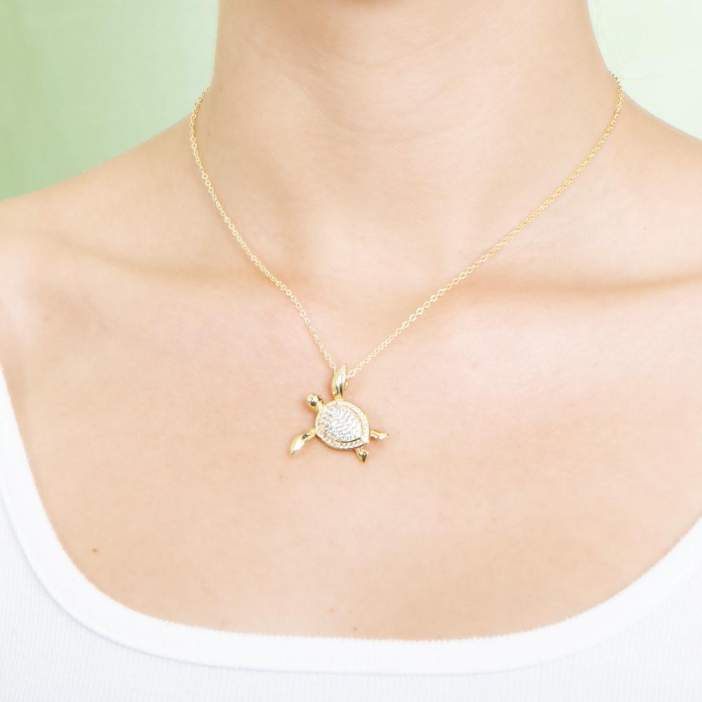 The picture shows a model wearing a 925 sterling silver, yellow gold vermeil, sea turtle pendant with topaz.