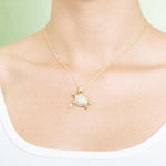 The picture shows a model wearing a 925 sterling silver, yellow gold vermeil, sea turtle pendant with topaz.