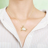 The picture shows a model wearing a 925 sterling silver, yellow gold vermeil, sea turtle pendant with topaz.