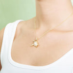 The picture shows a model wearing a 925 sterling silver, yellow gold vermeil, sea turtle pendant with topaz.