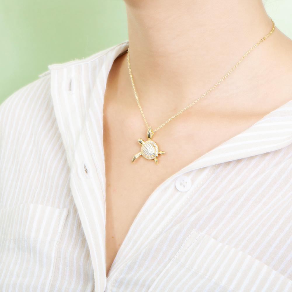 The picture shows a model wearing a 925 sterling silver, yellow gold vermeil, sea turtle pendant with topaz.