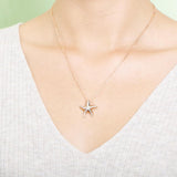 The picture shows a model wearing a 925 sterling silver, rose gold vermeil, starfish pendant with topaz.