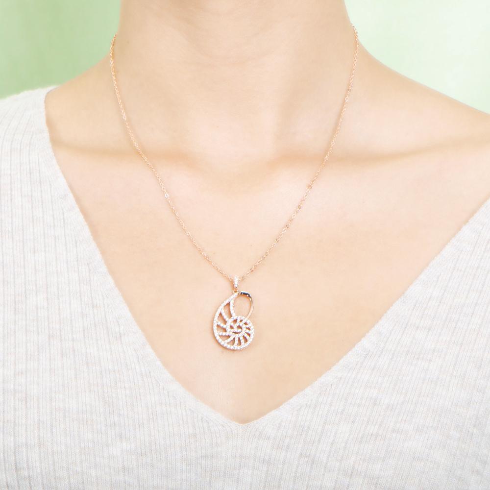The picture shows a model wearing a 925 sterling silver pavé rose gold vermeil nautilus shell pendant with topaz.