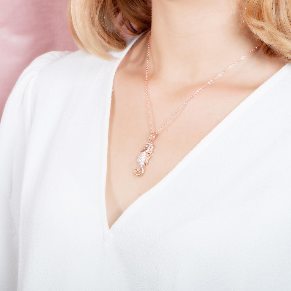 The picture shows a model wearing a 925 sterling silver, rose gold vermeil, pavé seahorse pendant with topaz.