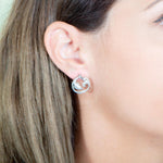 The picture shows a model wearing a 925 sterling silver swimming dolphin stud earring with topaz.