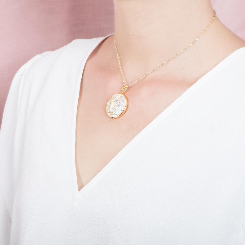 The picture shows a model wearing a 925 sterling silver, yellow gold vermeil, pavé whale tail medallion pendant with topaz.