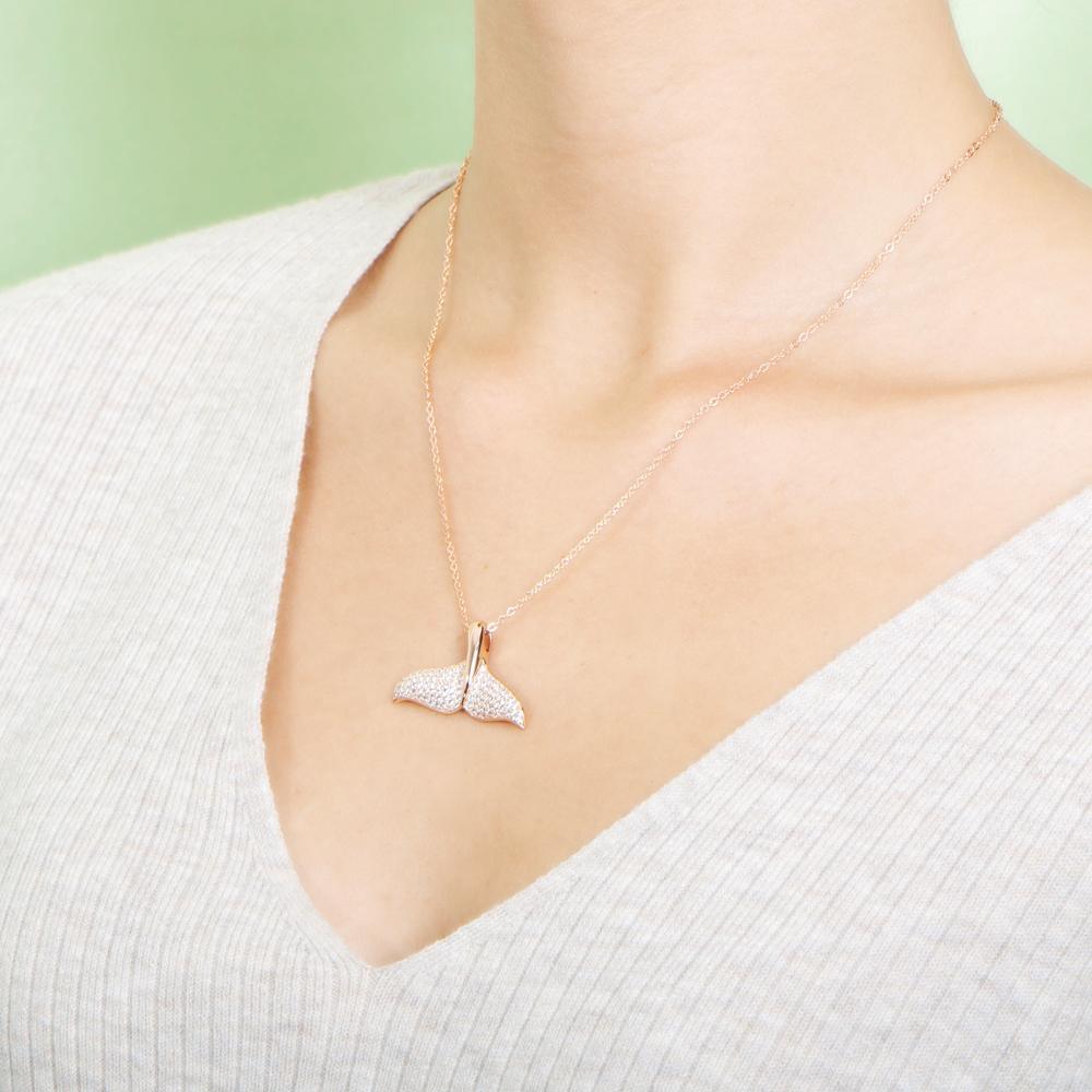 The picture shows a model wearing a 925 sterling silver, rose gold vermeil, pavé whale tail pendant with topaz.