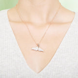 The picture shows a model wearing a 925 sterling silver, rose gold vermeil, pavé whale tail pendant with topaz.