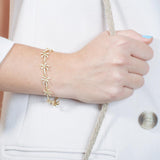 In this photo there is a model wearing a yellow gold plated palm tree bracelet with topaz gemstones.